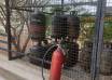 Domestic LPG cylinders stored in a metal cage beside a fire extinguisher