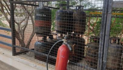 Domestic LPG cylinders stored in a metal cage beside a fire extinguisher