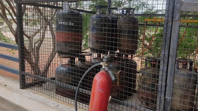 Domestic LPG cylinders stored in a metal cage beside a fire extinguisher
